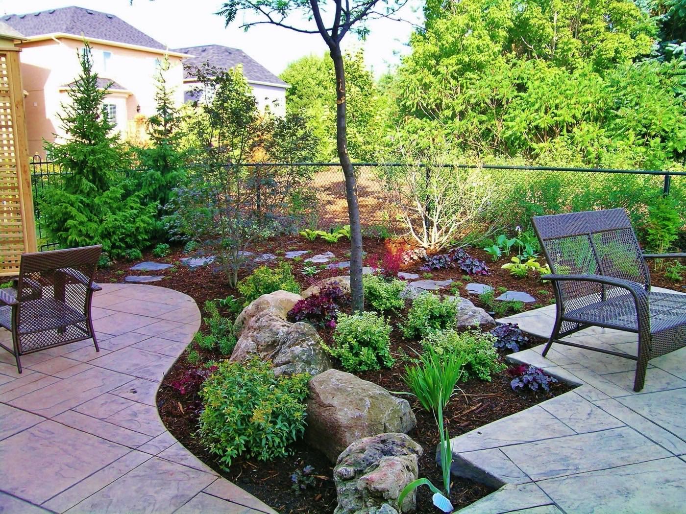 Paver patio with planted beds, boulders and outdoor chairs