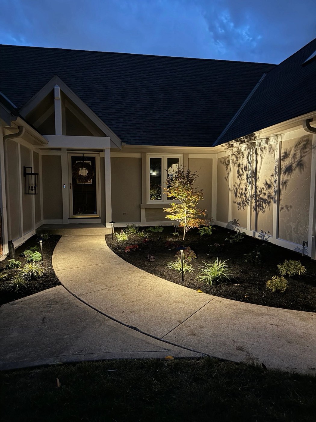Curved walkway and garden beds lit up at night