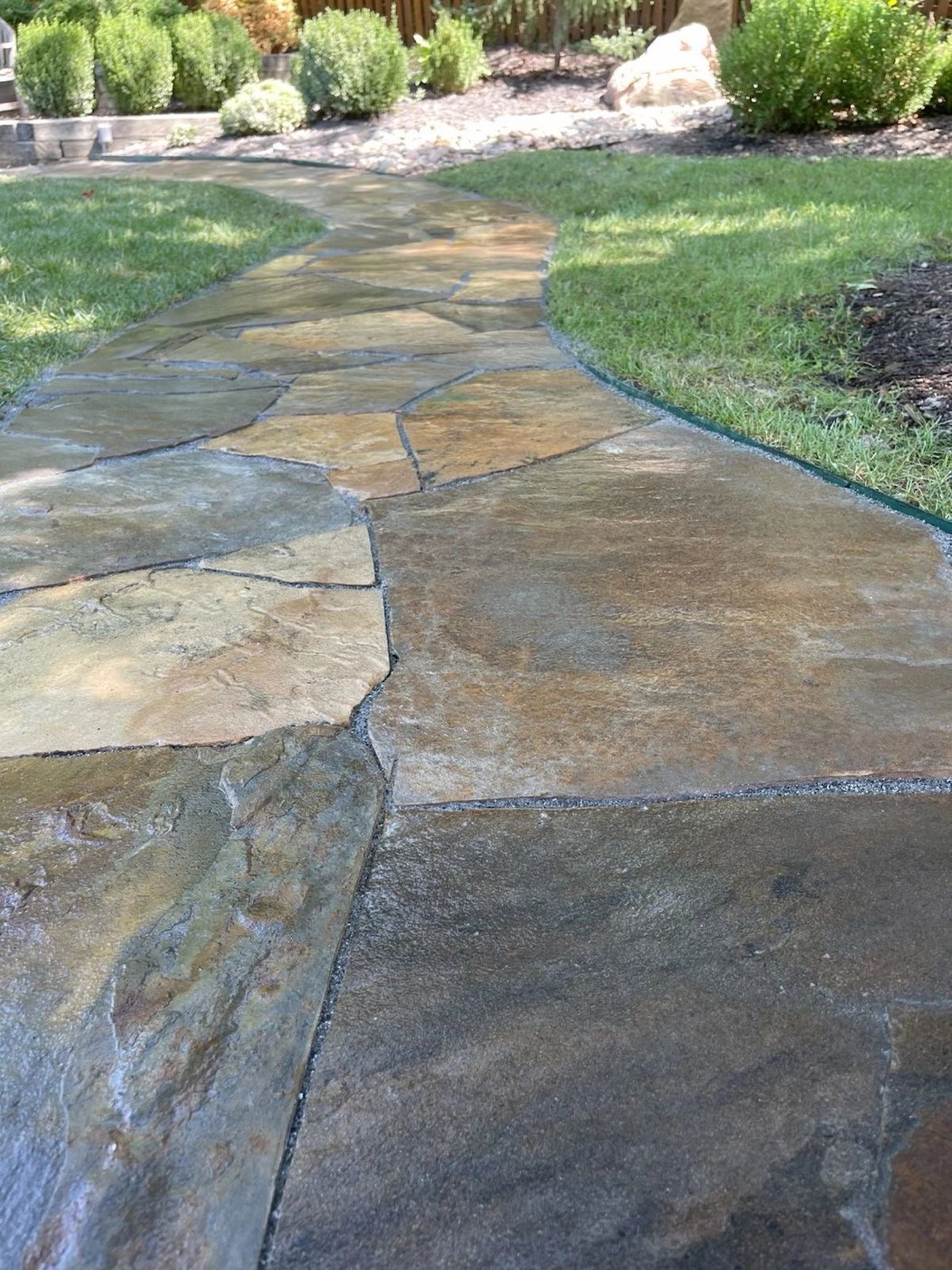 Flagstone path leading to shrubs and a lawn