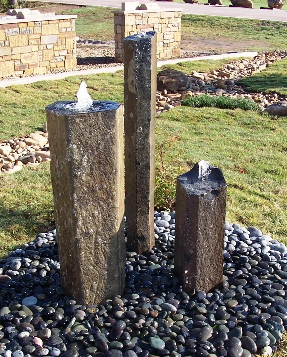 Basalt bubbling-rock fountain on a bed of black river rock