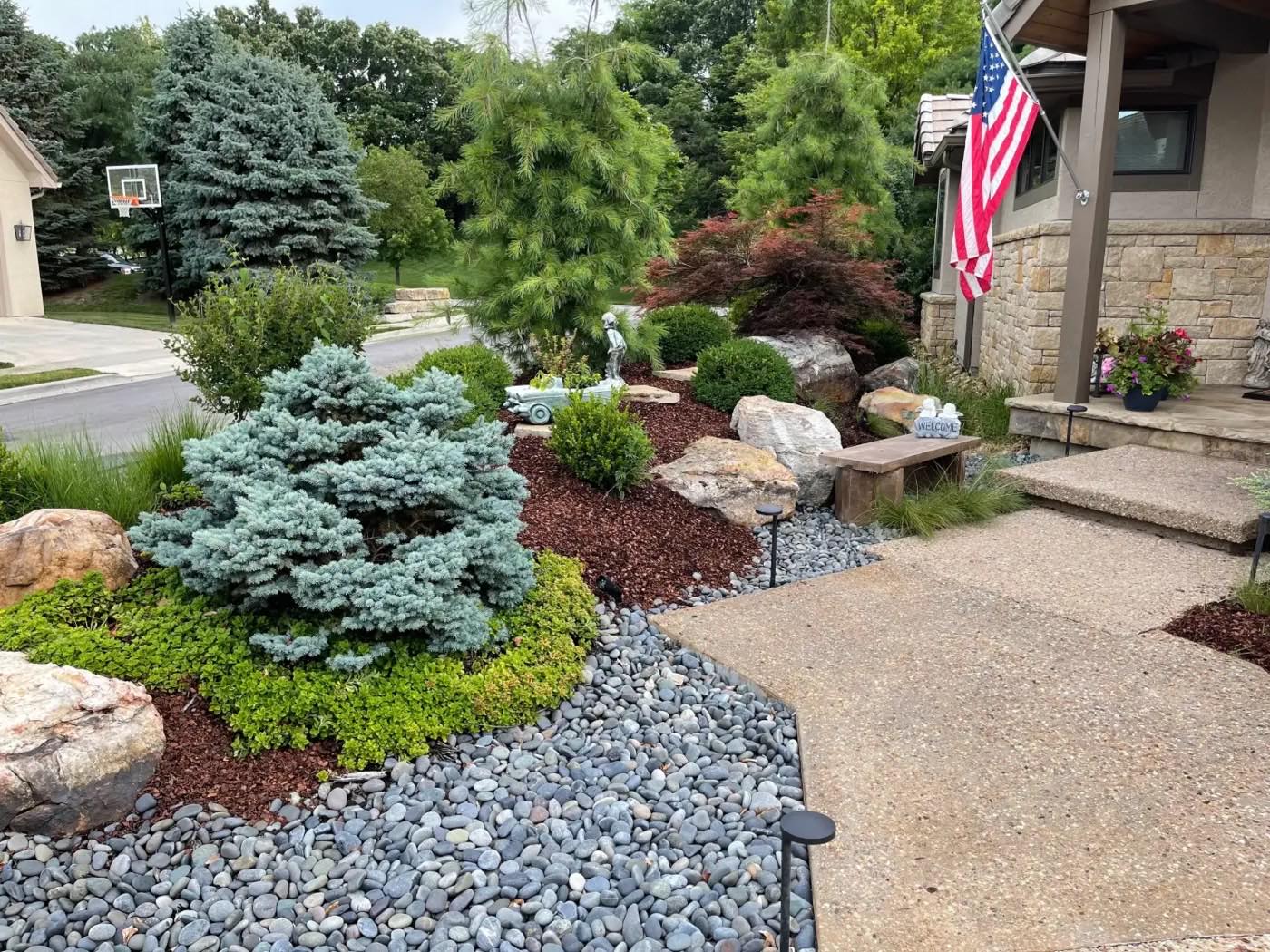 Front yard bed with a blue spruce, boulders, river rock and path lights